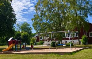 une aire de jeux en face d'un bâtiment rouge dans l'établissement Kroppefjäll B&B, à Dals Rostock