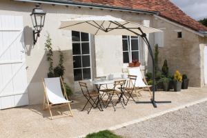 een tafel en stoelen onder een parasol op een patio bij Domaine de Praline l'ensemble in Villerbon