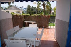 - une table et des chaises blanches sur la terrasse dans l'établissement Costa Ballena Cómodo Bajo con Piscina, Patio y 3 Dormitorios Parking free, à Rota