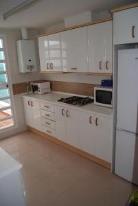 a kitchen with white cabinets and a microwave at Costa Ballena Cómodo Bajo con Piscina, Patio y 3 Dormitorios Parking free in Rota