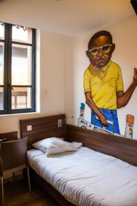 a bedroom with a picture of a man with sunglasses on the wall at Hôtel le Pastel in Toulouse