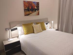 1 dormitorio con 1 cama blanca grande con almohadas amarillas en Apartamentos Vacacionales Joctis, Bajo B, en Fuengirola