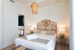 een slaapkamer met een groot wit bed en een kroonluchter bij Granada Luxury Apartments by Apolo Homes in Granada