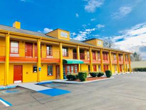 a large yellow building with red doors in a parking lot at Baymont by Wyndham Selma in Selma