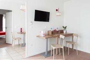 オルレアンにあるAppart'City Confort Orléansのテーブル、椅子、テレビが備わる客室です。