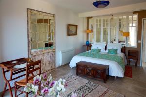 um quarto com uma cama, uma mesa e um espelho em Chambres d'hôtes Les 4 Vents Pointe du Hoc - Landing Beaches em Grandcamp-Maisy