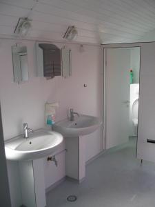 a white bathroom with two sinks and a toilet at Treene Camp Horn in Esperstoft