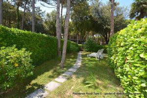 een bank in een tuin met een heg bij Villa a Lignano Pineta in Lignano Sabbiadoro