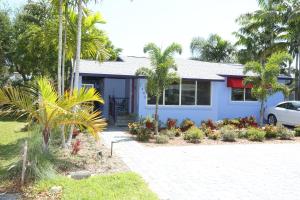 a blue house with palm trees and a driveway at Fantasy Island Inn, Caters to Men in Fort Lauderdale