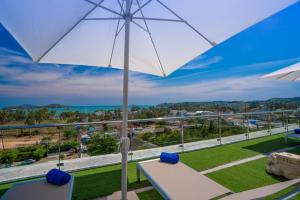 a balcony with an umbrella and a view of the ocean at Babylon Sky Garden - Long Term Holiday Rentals in Rawai Beach