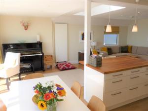 a kitchen and living room with a table and a piano at Pevensey Beach Retreat in Pevensey +13 photos