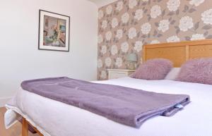 a bed with a purple blanket on top of it at Pevensey Beach Retreat in Pevensey