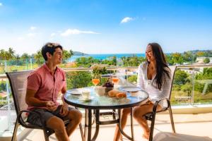 a man and woman sitting at a table on a balcony at Babylon Sky Garden - Long Term Holiday Rentals in Rawai Beach