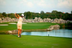 a woman is playing golf on a golf course at Terrazas Apartments by Bahia Principe in Tulum