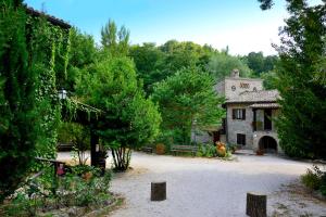 ein großes Steinhaus mit einem Hof mit Bäumen in der Unterkunft Agriturismo Le Querce di Assisi in Assisi