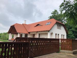 una casa blanca con un techo rojo detrás de una valla en Kiscsere Vendégház en Kállósemjén
