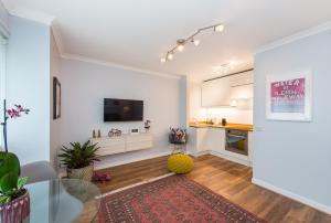 a living room with a glass table and a kitchen at Scottish Stays - The Allanfield Apartment in Edinburgh