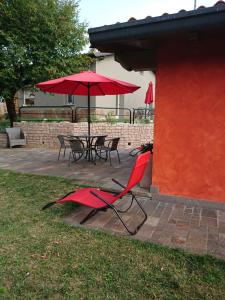 2 sillas rojas y una mesa con sombrilla roja en Il carpino bianco bilocale, en Puegnago sul Garda