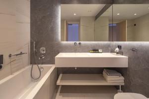 a bathroom with a sink and a tub and a mirror at Skiathos Palace Hotel in Koukounaries