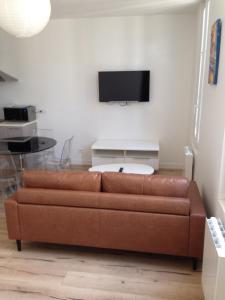 a living room with a brown couch and a tv at Joli appartement 40m2 entièrement équipé idéal pour location thermale ou saisonnier in Rochefort