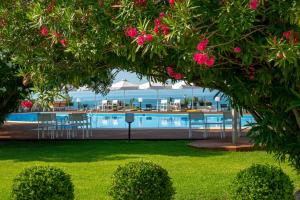 a pool with tables and chairs and pink flowers at Skiathos Palace Hotel in Koukounaries