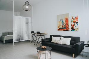 a living room with a black couch and a table at Prima Gardens City Studios in Larnaca