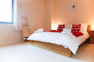 ein Schlafzimmer mit einem großen Bett mit roten und weißen Kissen in der Unterkunft Horizon Canary Wharf Apartments in London