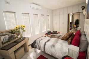 1 dormitorio con cama, tocador y espejo en John-Lou's One-bedroom Apartment, en Windhoek