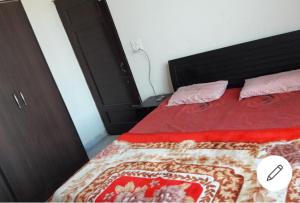 uma cama com um edredão vermelho e almofadas cor-de-rosa em Angad home fully furnished Ac wifi included ground floor em Kharar