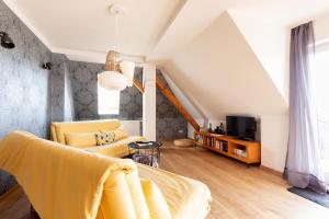 ein Wohnzimmer mit einem gelben Sofa und einem TV in der Unterkunft Maisonette Wohnung mit Blick über die Stadt in Jena