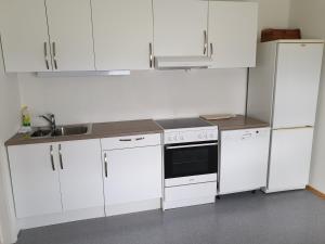 a white kitchen with white cabinets and a sink at Søndre Berg gate 20 Apartement in Vardø +1 photo