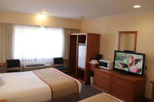 ein Hotelzimmer mit einem Bett und einem Flachbild-TV in der Unterkunft Travelodge by Wyndham Kamloops in Kamloops