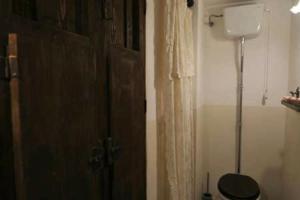 a bathroom with a toilet and a wooden door at B&B del Giglio in Cefalù