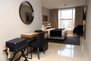 a bedroom with a bed and a desk and a mirror at Agua del Corral Hotel & Spa in Mendoza