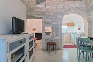 een woonkamer met een tv en een keuken bij Casa Le Mura in Ostuni