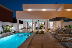 Villa Deluxe Suites Maspalomas في ماسبالوماس: مسبح في فندق مع كراسي ومظلة