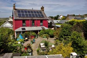 a red house with solar panels on the roof at Western House in Llangennith