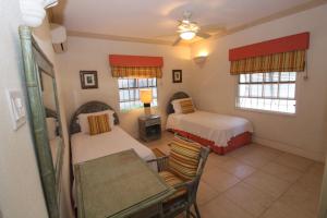基督教堂市Beachfront Apartment in St. Lawrence Gap - Close To Your Every Need的一间卧室，有两张床、一张桌子和几把椅子