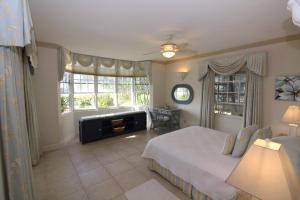 a bedroom with a bed and a large window at Beachfront Apartment in St. Lawrence Gap - Close To Your Every Need in Christ Church