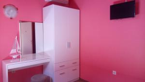 a room with a pink wall with a mirror and a tv at B&B Eva in Ičići