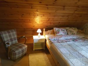 a bedroom with a bed and a chair in a cabin at Wyspa Świerków in Lipusz
