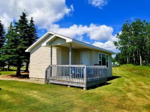 a small house with a large porch in a yard at Seascape Coastal Retreat - ADULTS ONLY - HOT TUBS in Ingonish