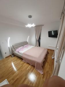 1 dormitorio con 1 cama en una habitación con suelo de madera en Apartman Lux Doboj en Doboj