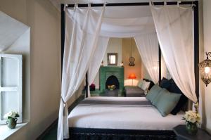 1 dormitorio con cama con dosel y chimenea en Riad Vert, en Marrakech