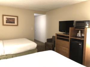 a hotel room with a bed and a flat screen tv at The Grand Inn Peoria in Peoria