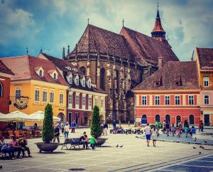a group of people sitting on benches in front of a building at Belle View Apartment Brasov in Braşov