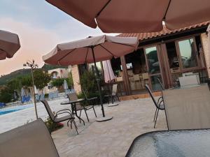 a patio with chairs and umbrellas next to a pool at Daniel Hotel in Kalamaki