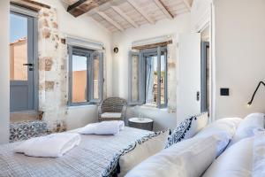 a bedroom with white walls and windows and a bed with pillows at Aoria Estate Old Port in Chania Town