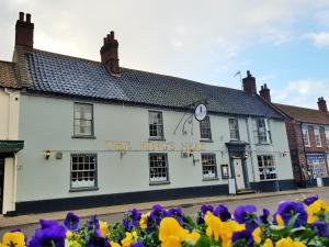 a white building with flowers in front of it at Kings Head Holt in Holt