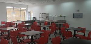 an empty room with tables and red chairs at Pousada Femcut in Itanhaém